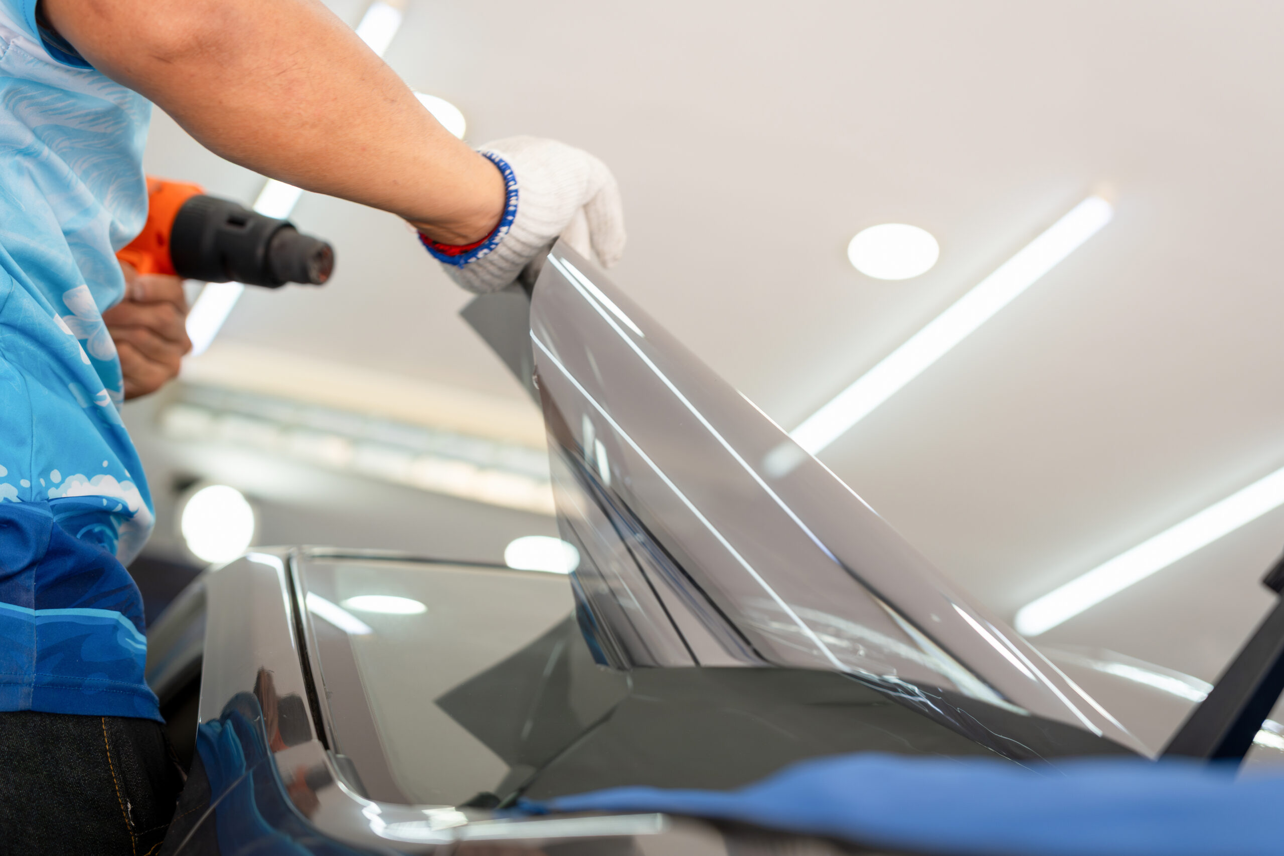 Worker man tinting car window with heat gun in workshop, Male specialist applying car tinting film
